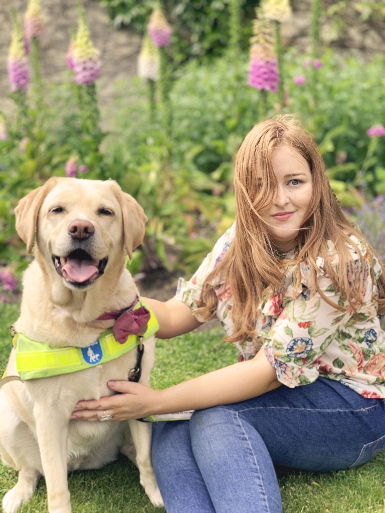 Emily sitting with Unity - a yellow labrador in the setting of a summers garden in Bath.