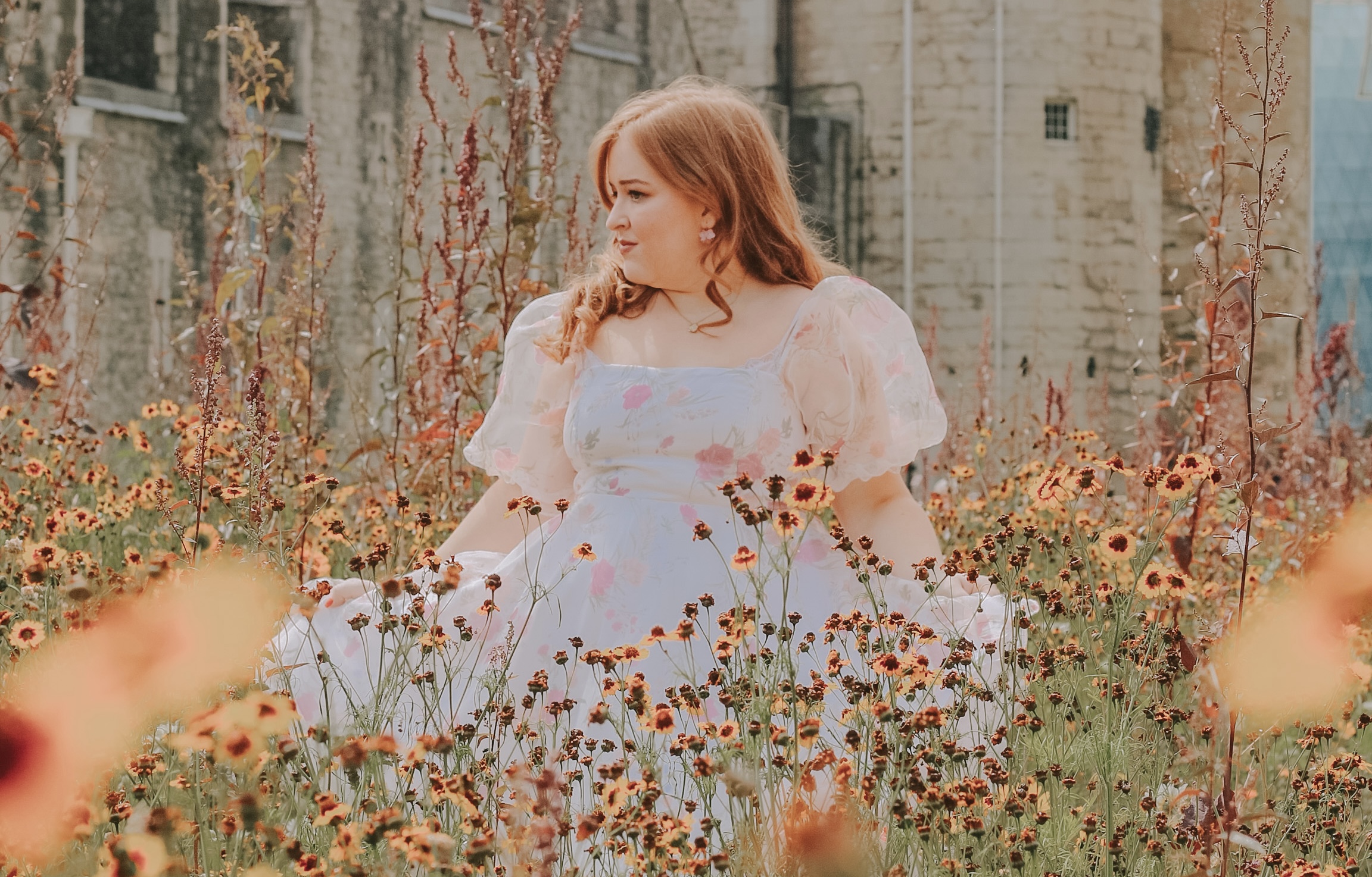 A photo of Emily standing in a widflower meadow