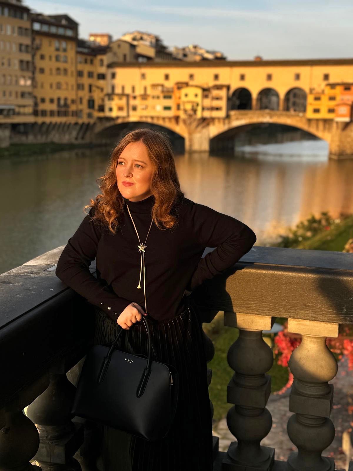 A photo of Emily standing at Ponte Vecchio Bridge.